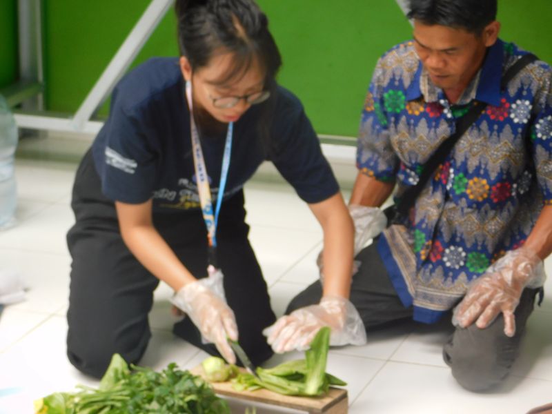 Salah satu anggota kelompok tani TTS sedang mengamati proses pengolahan sawi oleh Mahasiswi KKN IPB